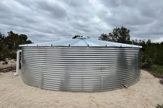 Silver corrugated Pioneer water storage tank in sandy outdoor setting
